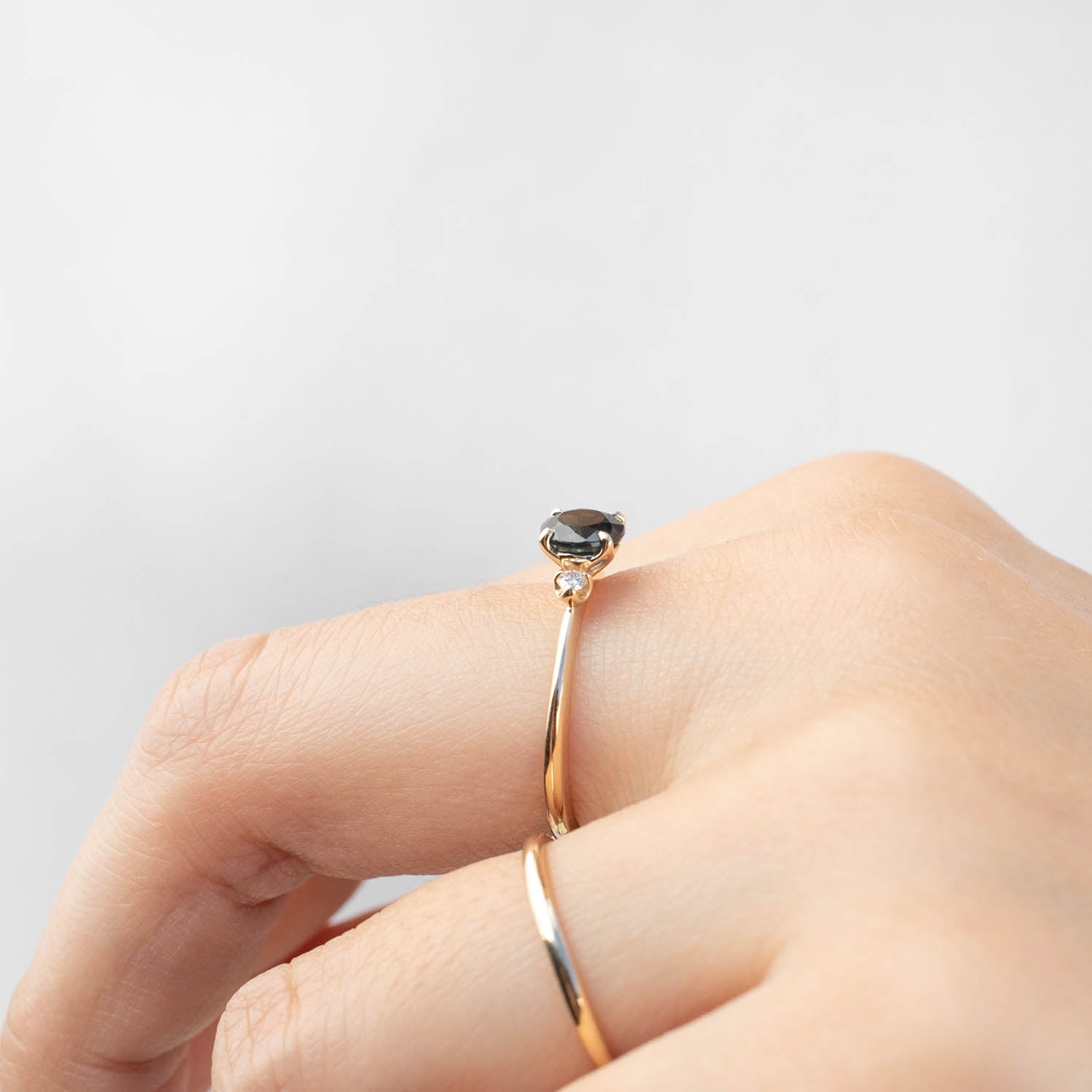 Sofia Ring featuring 1ct Queensland Dark Peacock Sapphire set in 14k yellow gold with side white diamonds on hand model.