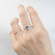 Hand wearing one of a kind Nina Ring with 1.22ct teal blue Montana sapphire set in 14k rose gold band