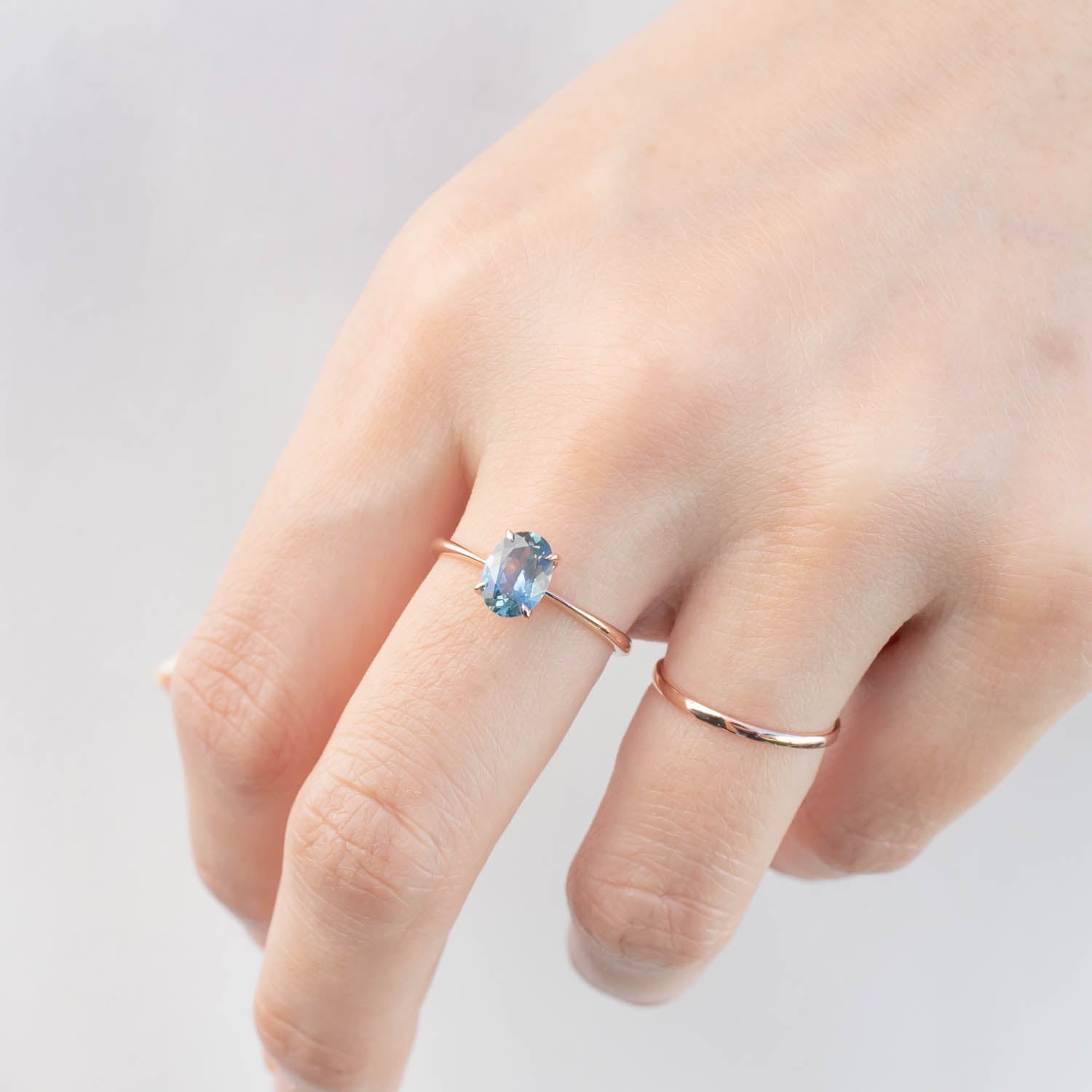 14k rose gold ring with 1.22ct teal blue Montana sapphire on a hand, delicate tapered band design