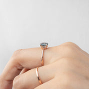 Close-up of a hand wearing a Nina Ring with a 1.22ct teal blue Montana sapphire in 14k rose gold band