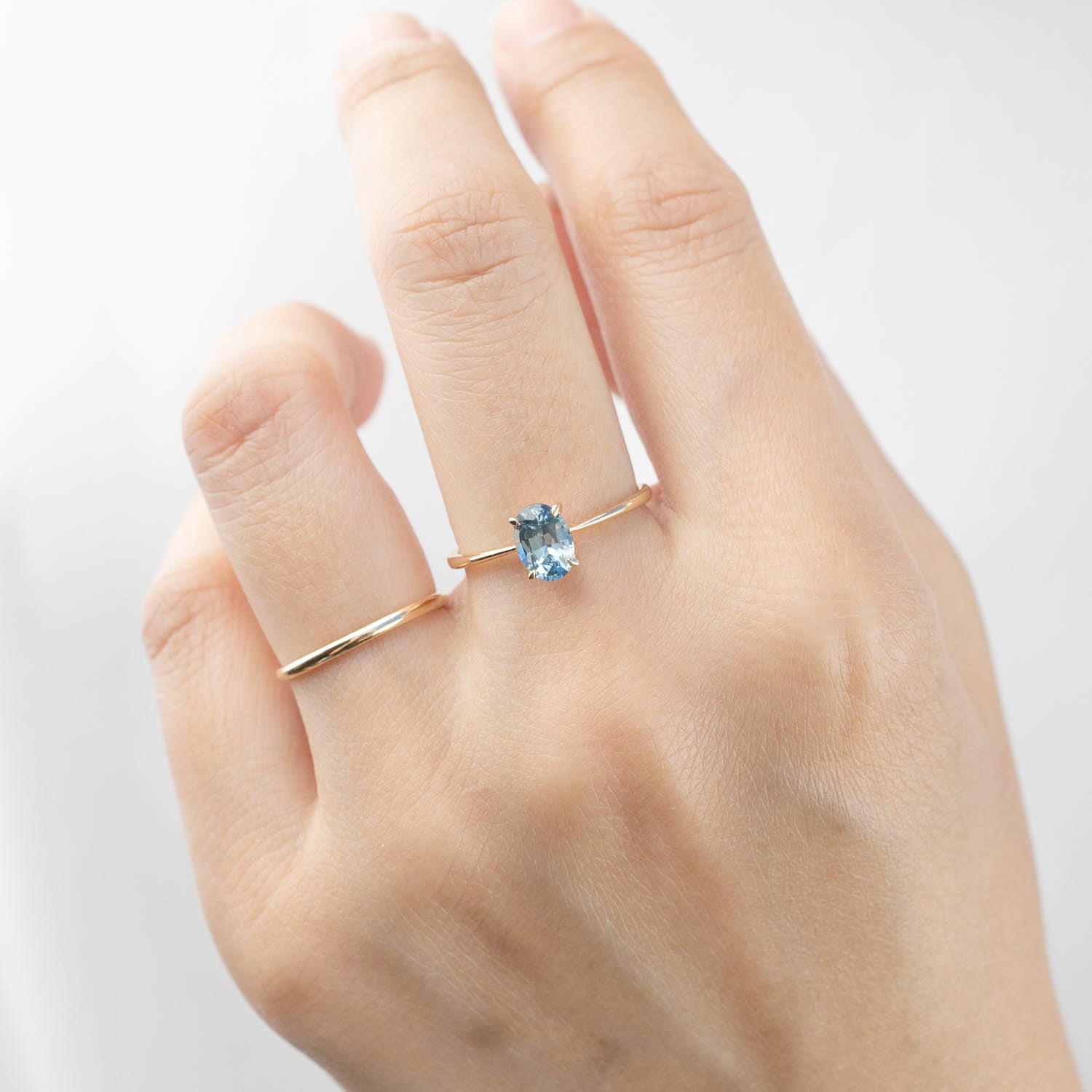 Hand wearing Nina Ring with 0.98ct blue Montana sapphire set in 14k rose gold adjustable band