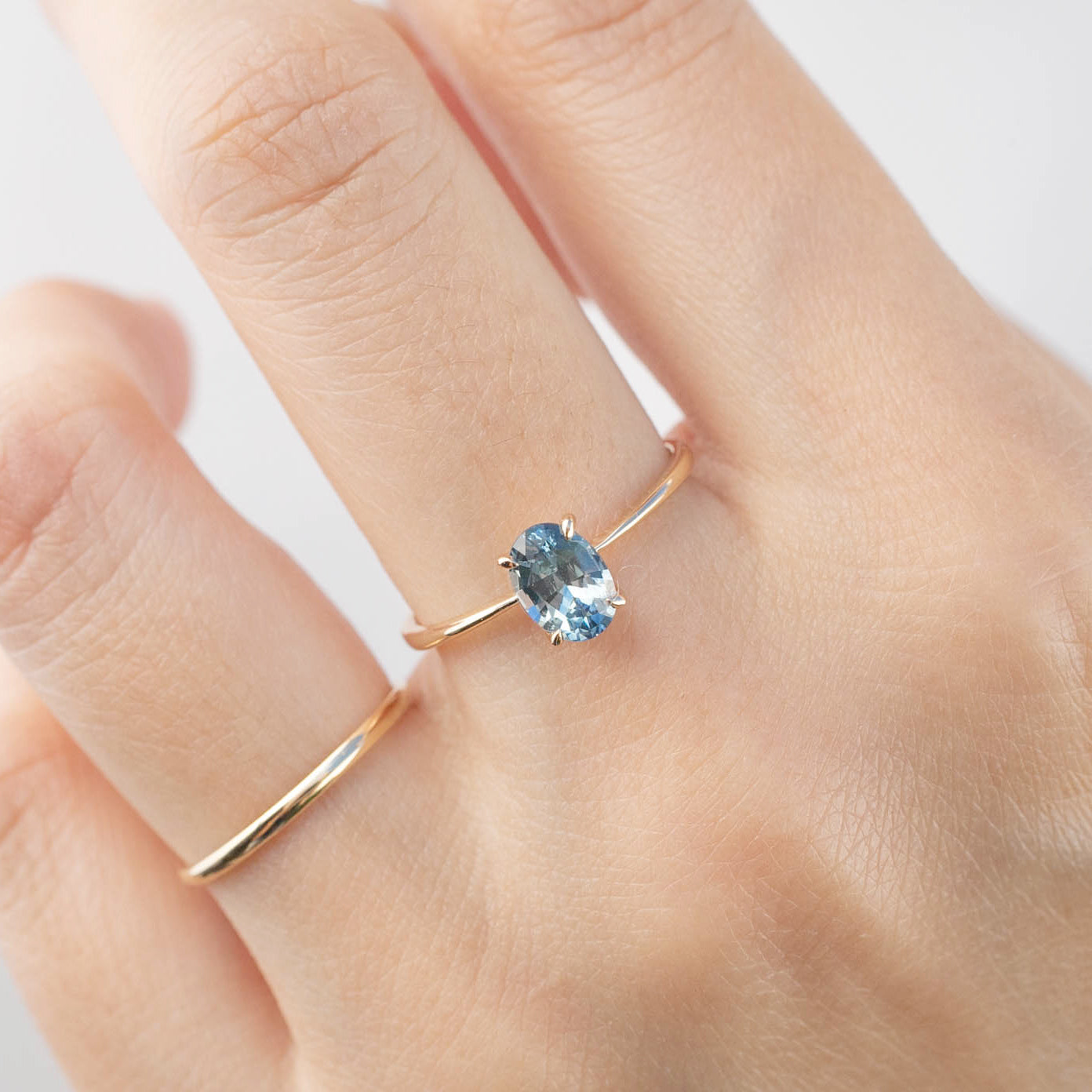 Close-up of a hand wearing a Nina Ring with 0.98ct blue Montana sapphire set in 14k rose gold band.