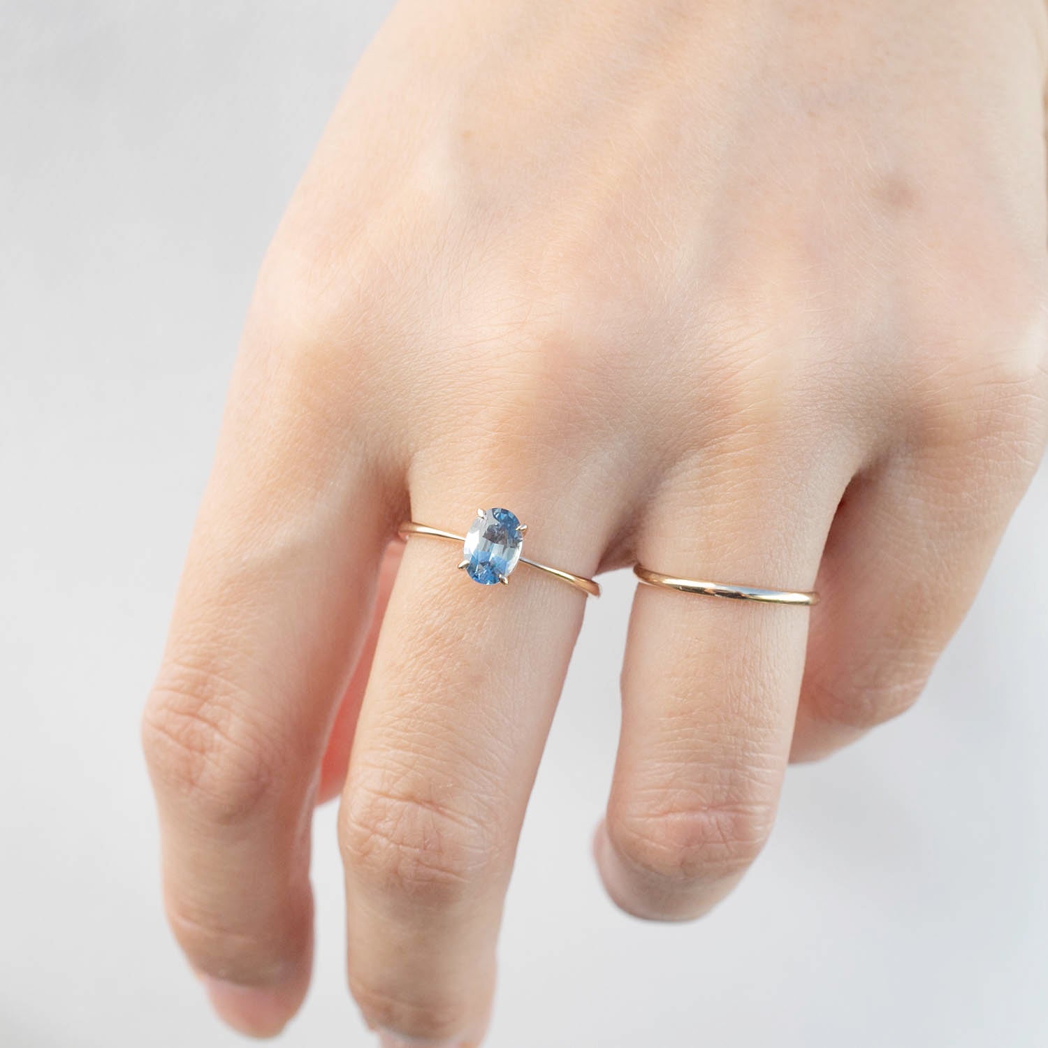 Hand wearing a size 7 rose gold Nina Ring featuring a 0.98ct oval blue Montana sapphire gemstone