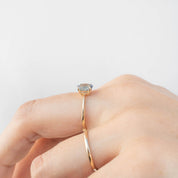 Close-up of a hand wearing a Nina Ring with a 0.98ct Blue Montana Sapphire set in recycled 14k rose gold band