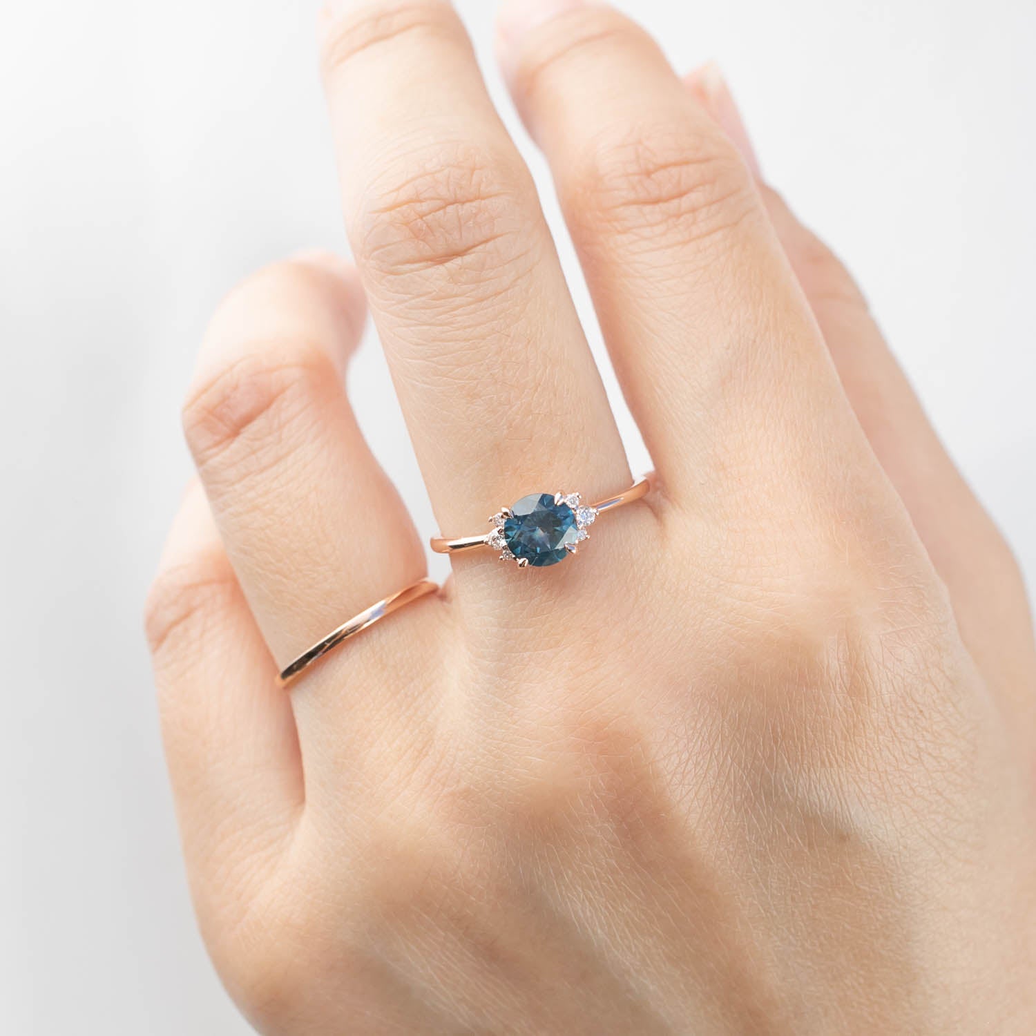 Hand wearing Lena Ring with 1.15ct teal blue Montana sapphire set in 14k rose gold band