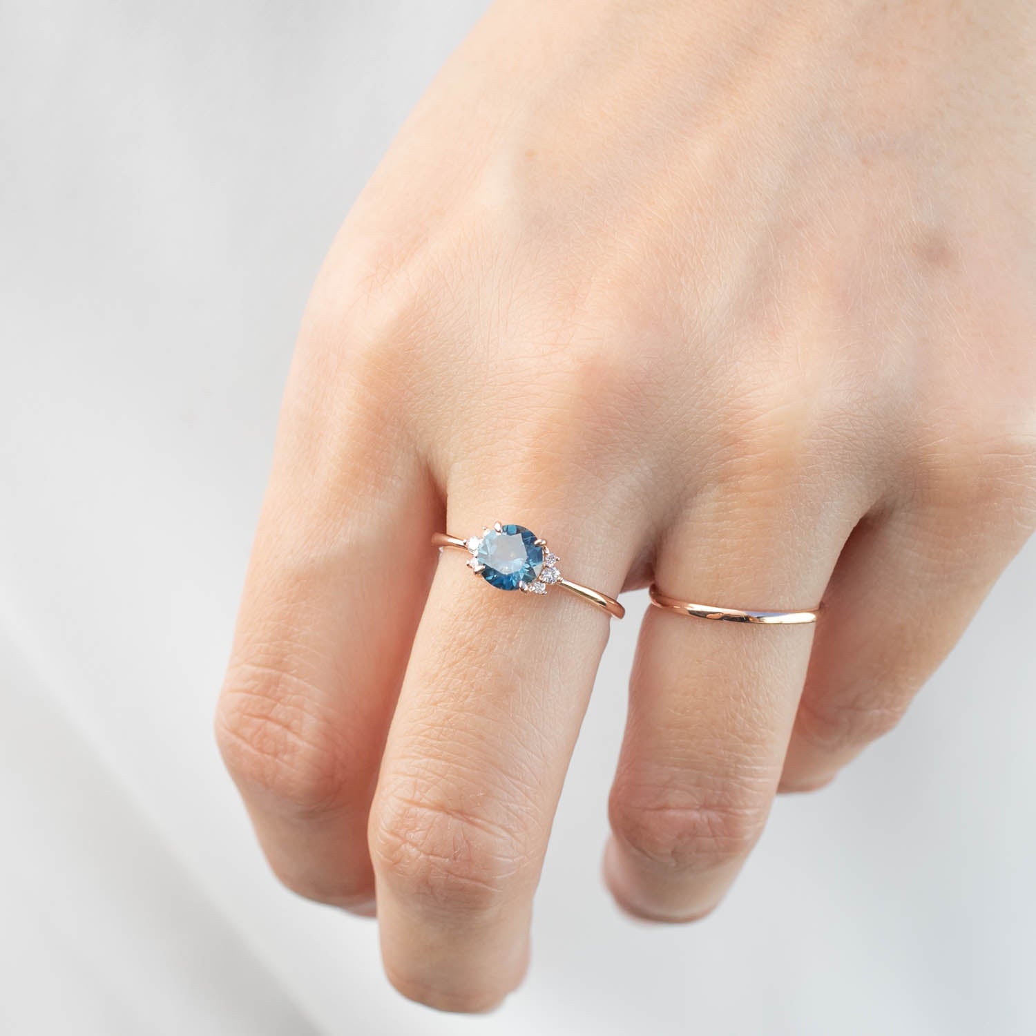 Delicate rose gold ring featuring 1.15ct teal blue Montana sapphire with diamond accents on hand.