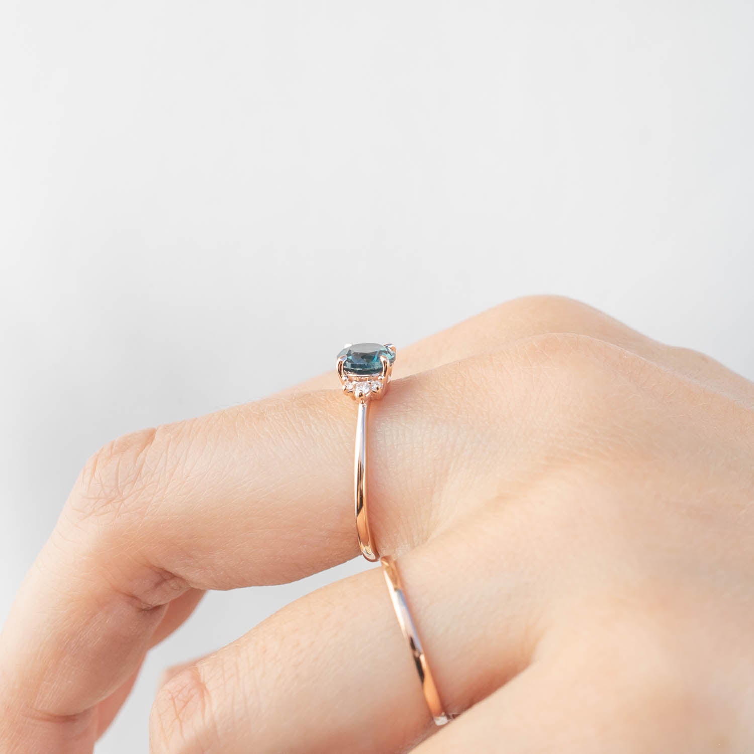 Close-up of a hand wearing a rose gold ring with a 1.15ct teal blue Montana sapphire in a four-prong setting