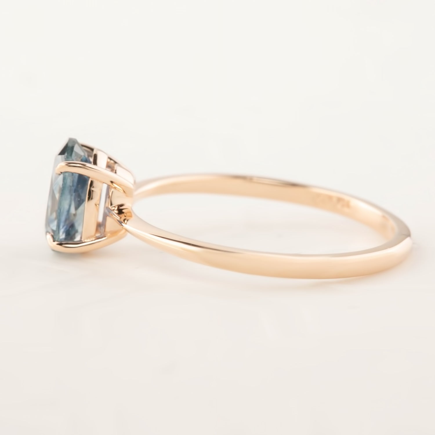 Side view of Nina Ring with 1.22ct teal blue Montana sapphire set in 14k rose gold band
