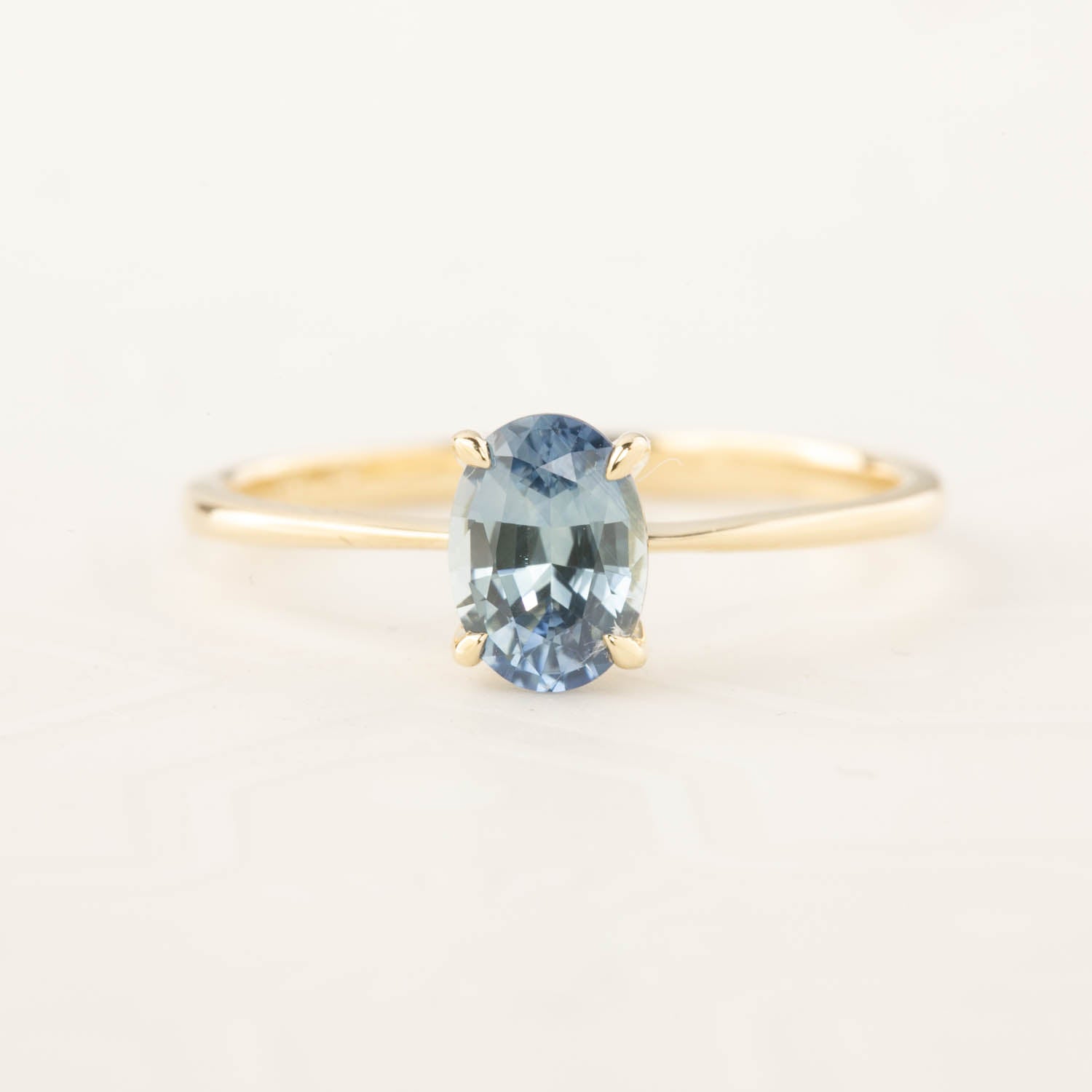 Close-up of a 0.98ct oval blue Montana sapphire ring set in recycled 14k rose gold with a tapered band