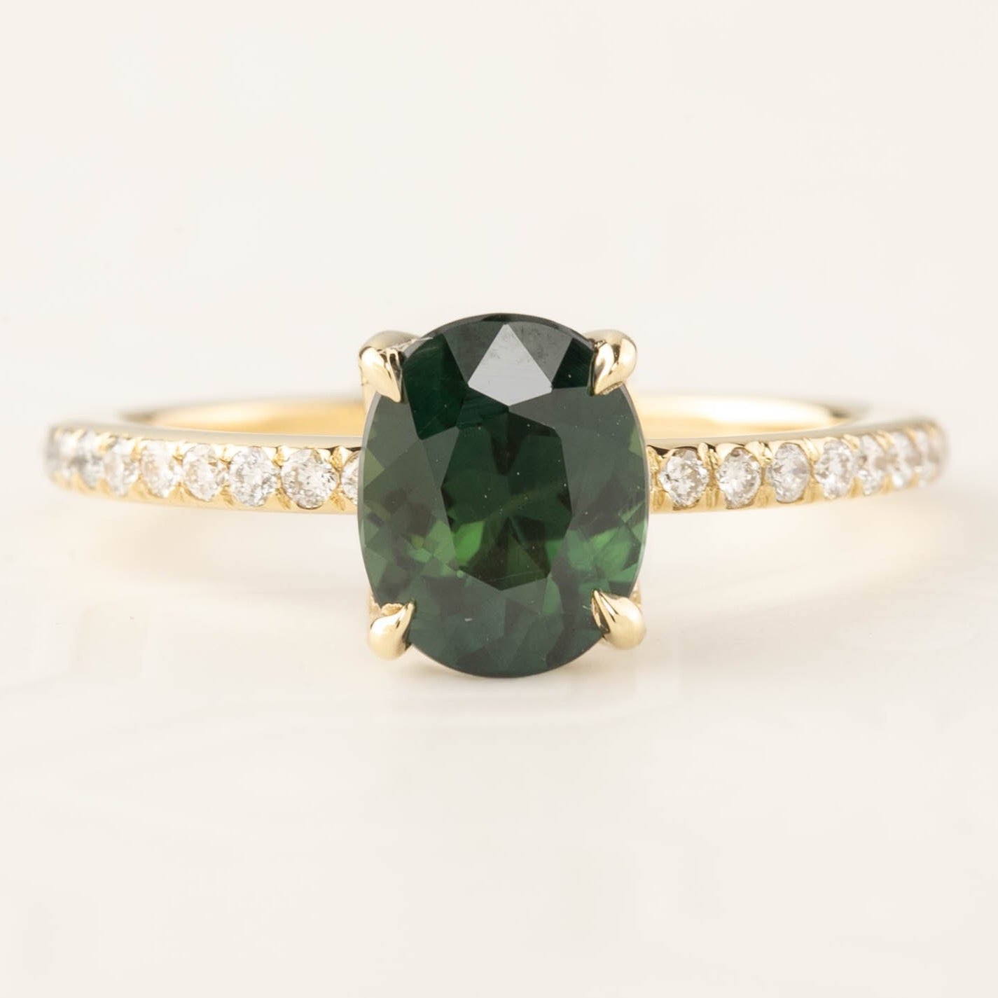 Maria Setting(Oval cut) gold ring with a deep green oval gemstone and sparkling white accent diamonds on band