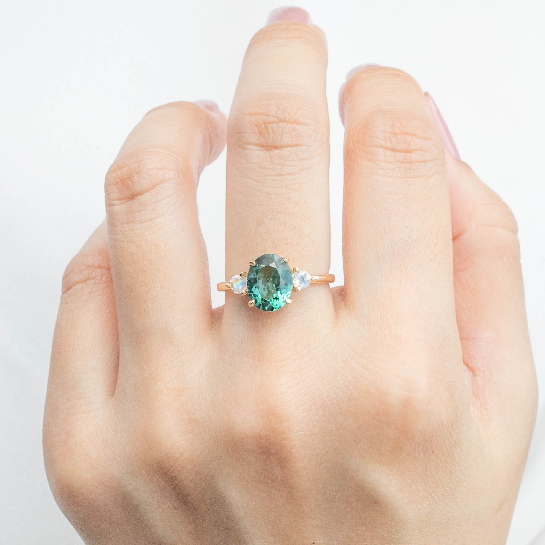 Hand wearing Emilie Ring with 2.09ct green tourmaline and moonstone, handmade, ethically sourced, 14k yellow gold band