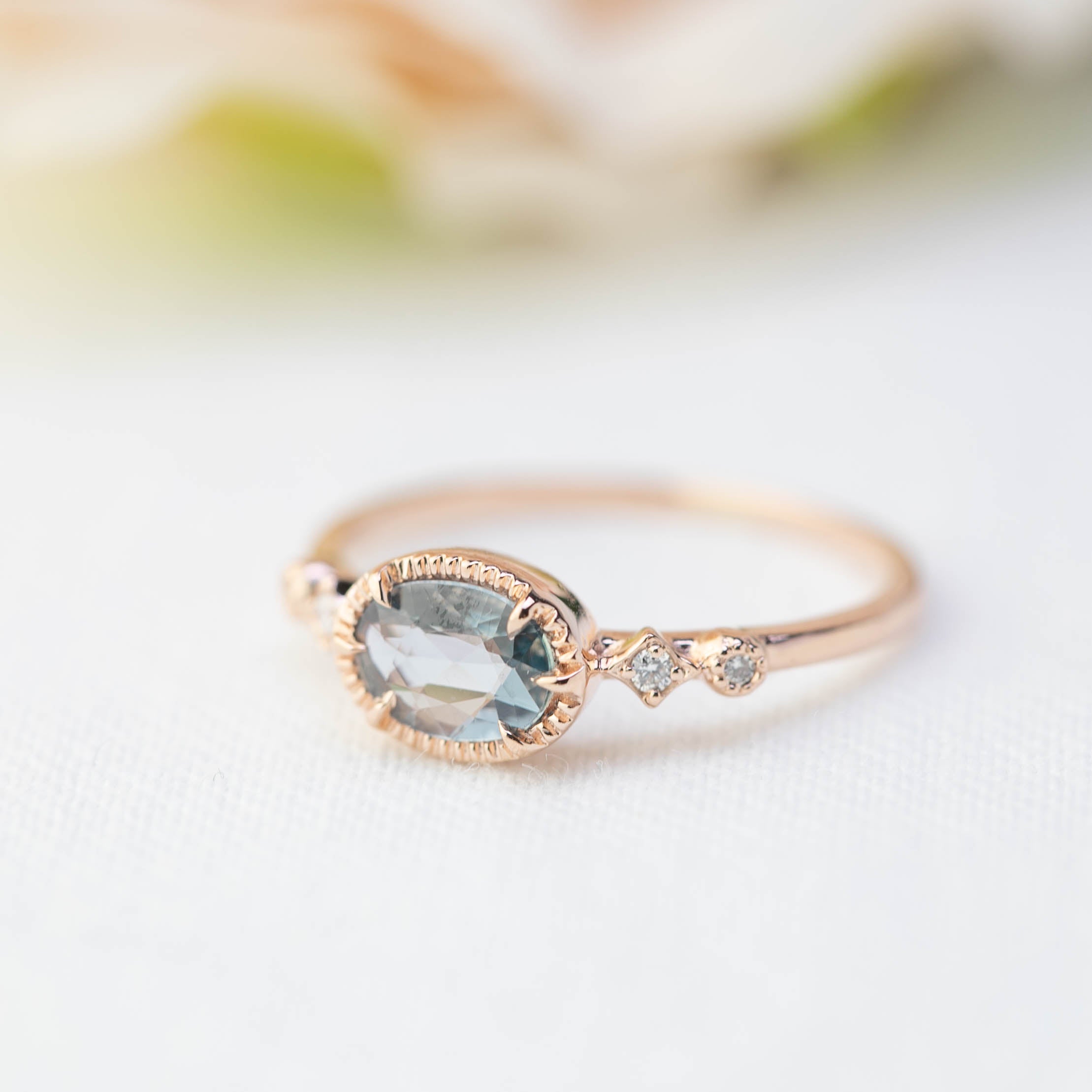 Rose gold ring with 0.8ct blue sapphire and small white diamonds in a delicate bezel setting