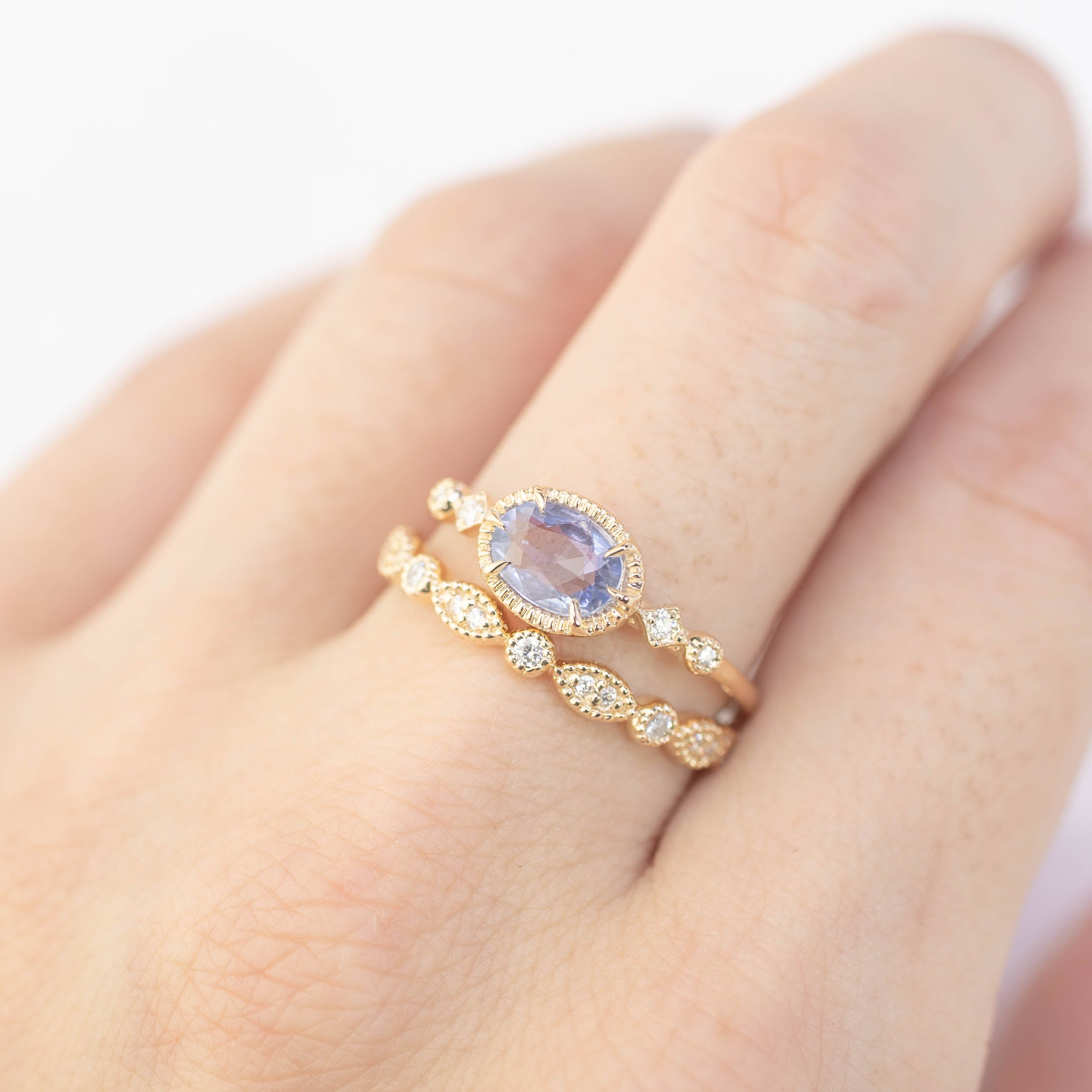 Close-up of hand wearing a 0.8ct blue sapphire Stella ring in 14k rose gold with diamond accents