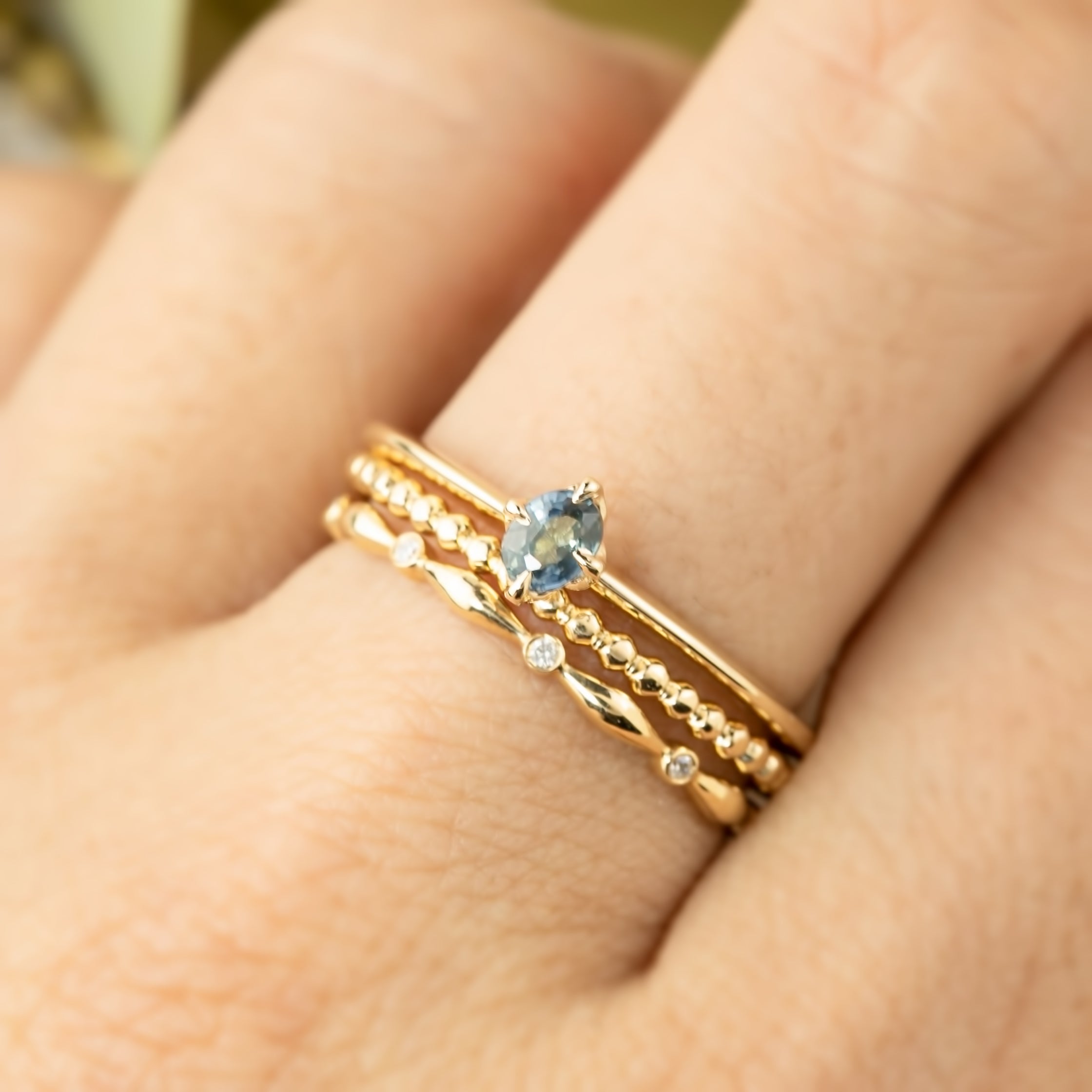 The Alice sapphire ring stacked with different gold bands to show its dainty, minimalist profile.