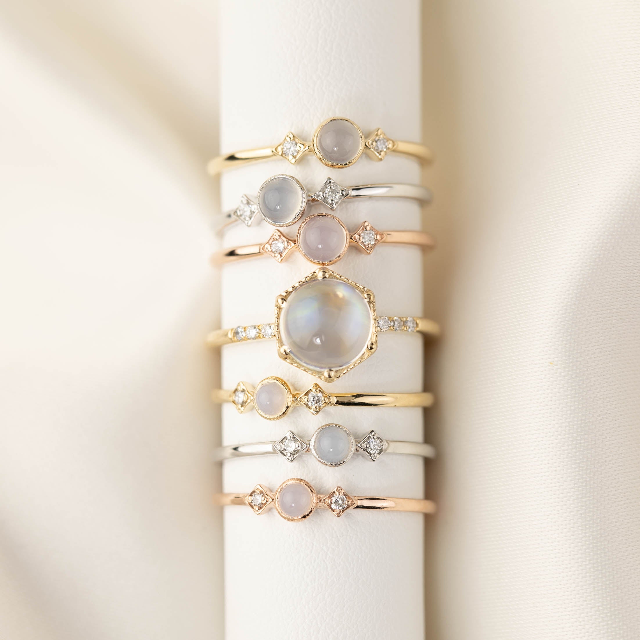 Stack of delicate 14k gold, rose gold, and white gold rings featuring cabochon rainbow moonstones and white diamonds