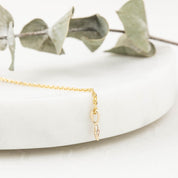 Close-up of a delicate 14k gold star charm with a 1.5mm bezel set birthstone on a fine chain.