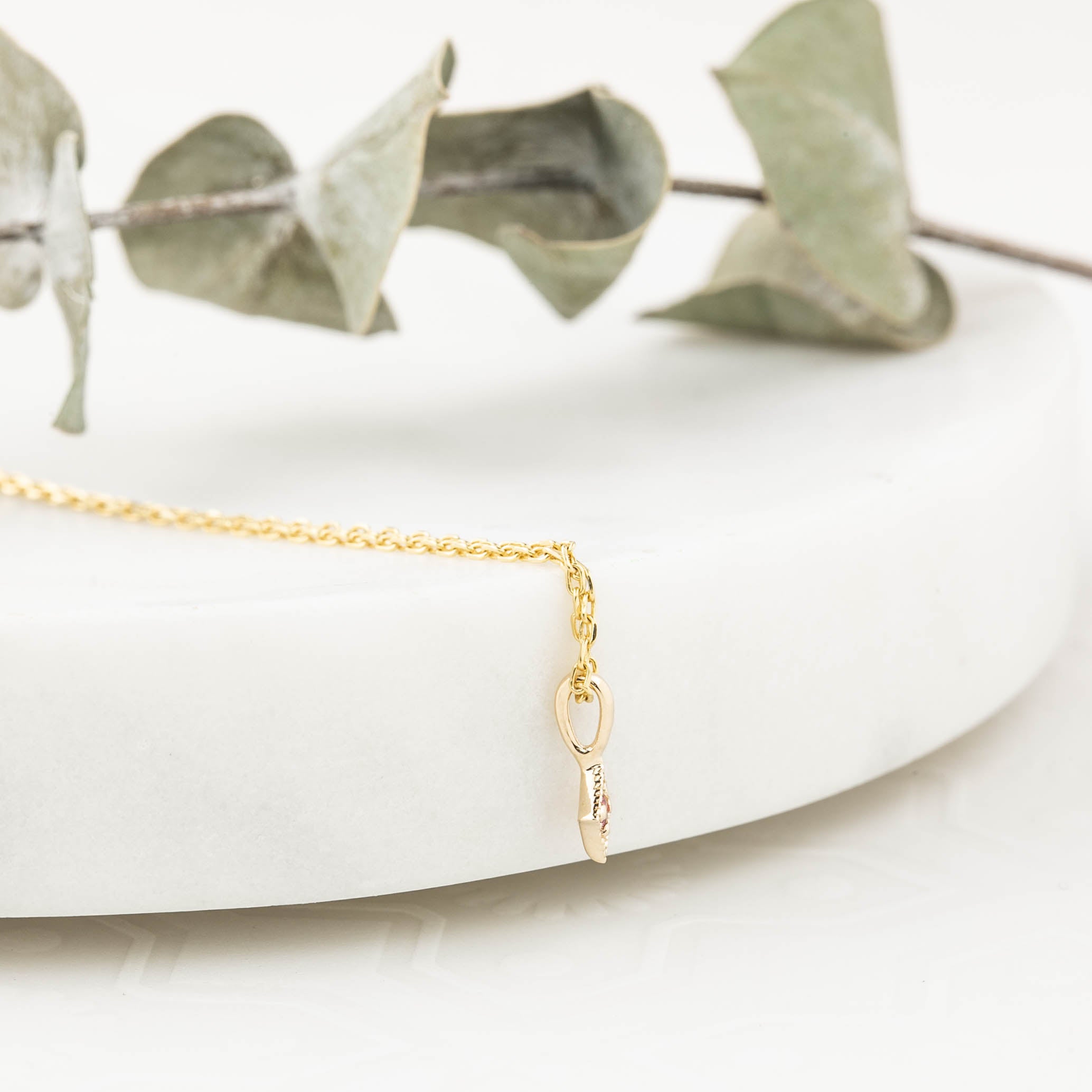 Close-up of a delicate 14k gold star charm with a 1.5mm bezel set birthstone on a fine chain.