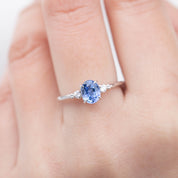 Close-up of Estel ring with 1.01ct Blue Ceylon sapphire and white diamonds set in 14k white gold on a finger.