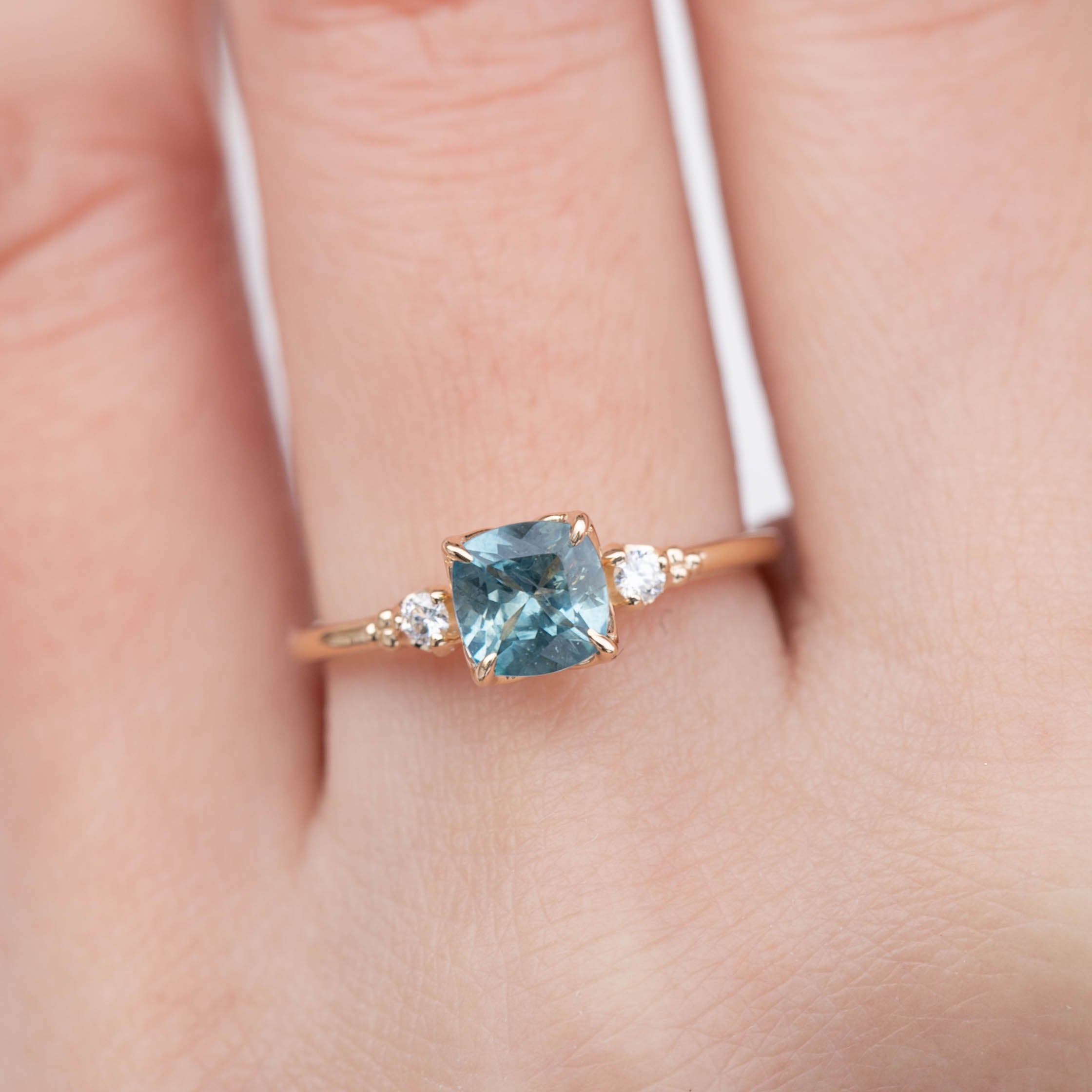 Estel Ring featuring a 1.07ct cushion cut light blue green Montana sapphire with diamond accents on recycled gold band