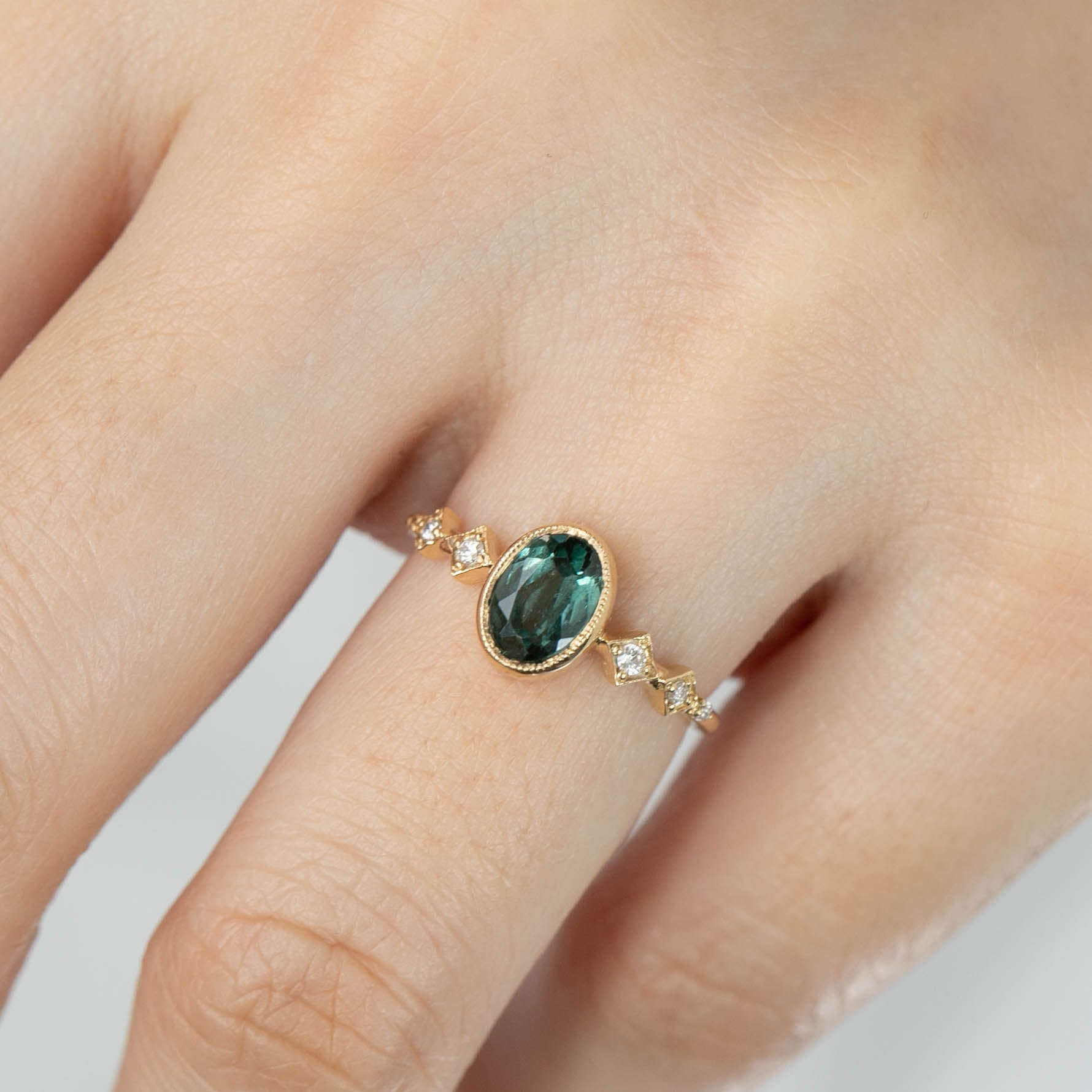 14k yellow gold ring with 1.02ct green tourmaline and white accent diamonds on finger low profile bezel setting