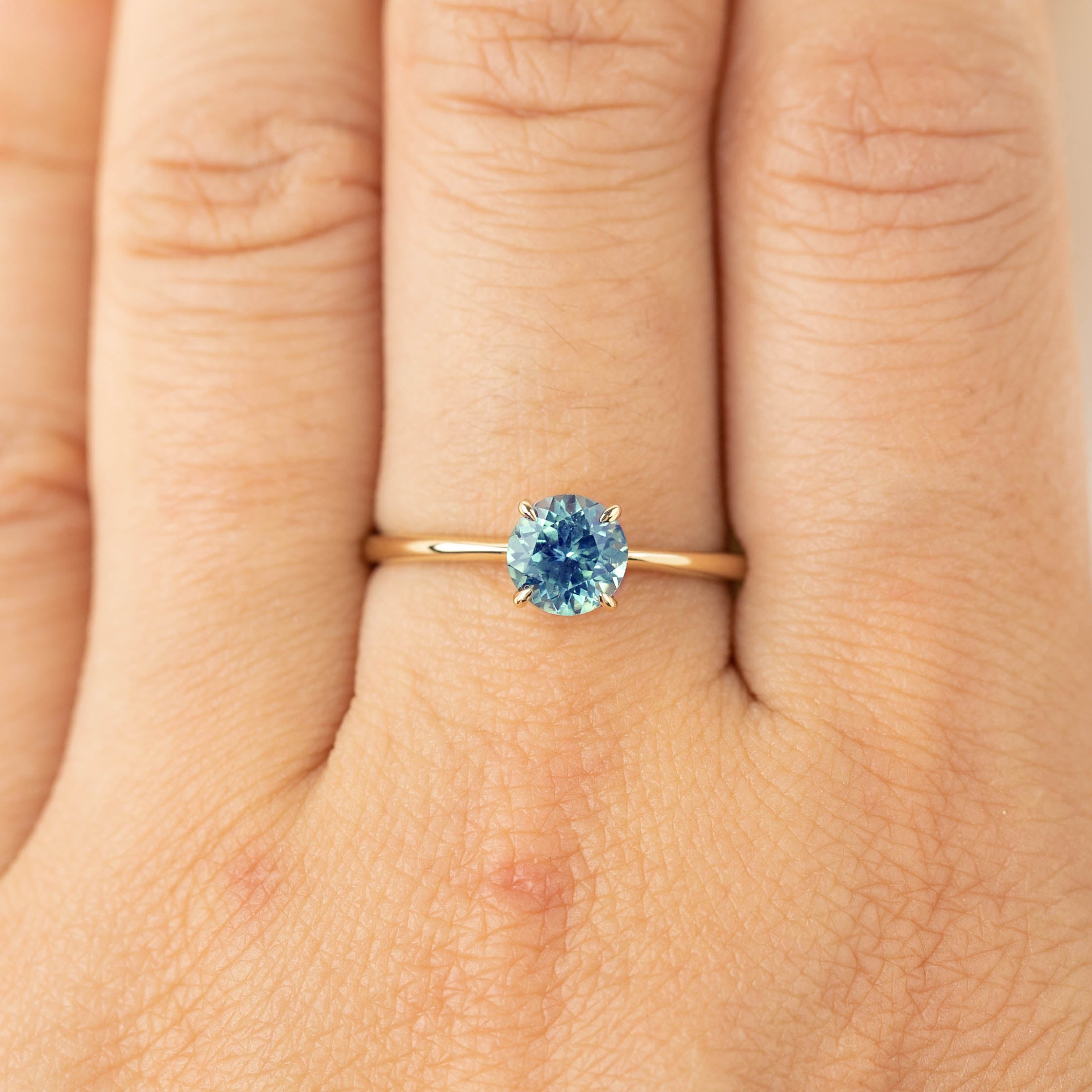 0.94ct light blue Montana sapphire ring in 14k recycled yellow gold with classic 4-prong setting on finger