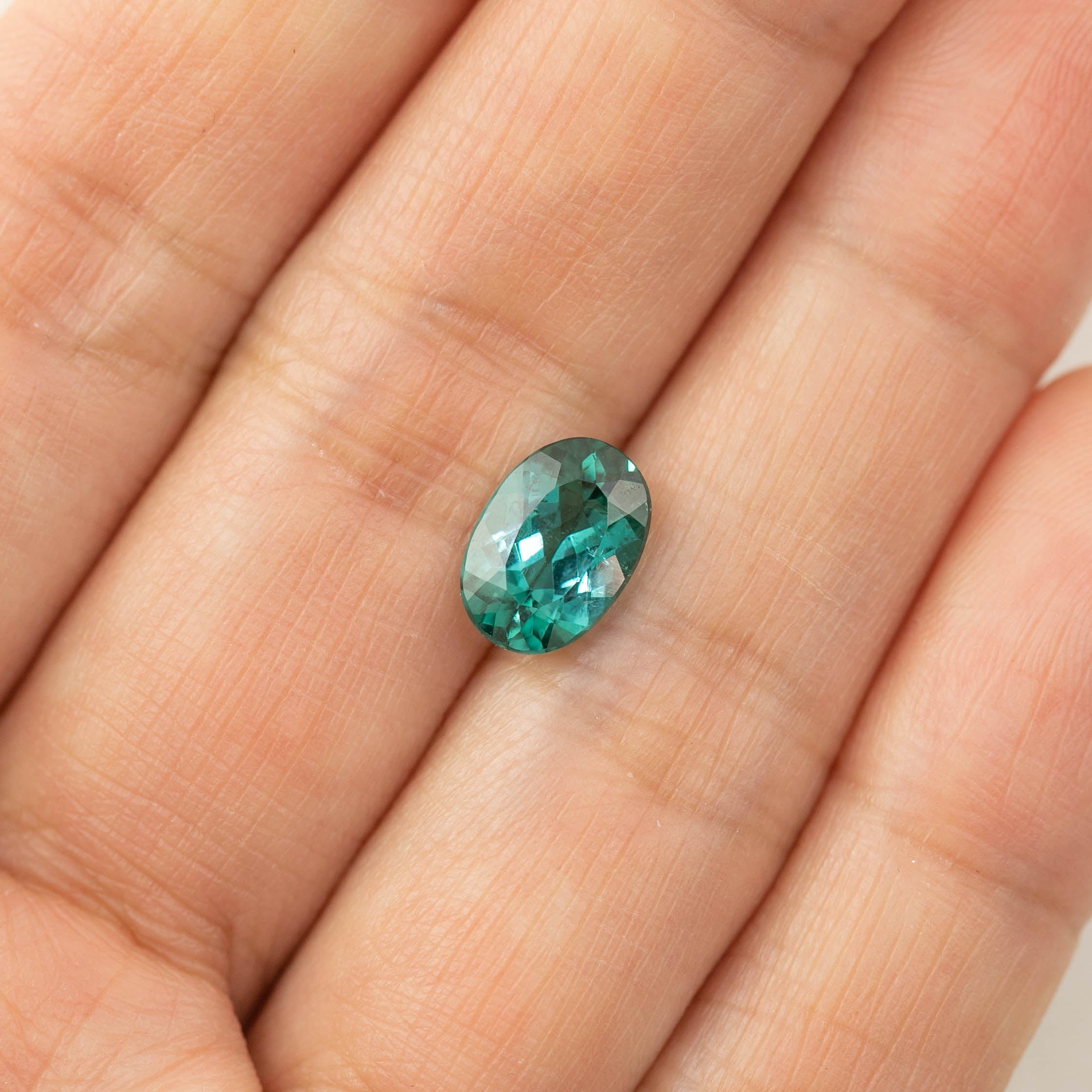 1.88ct oval cut emerald green tourmaline gemstone on a hand, heat treated, 9.5mm x 6.6mm x 4.3mm, Namibia origin