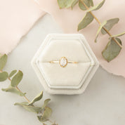 Oval rose cut diamond ring with gold tapered band in a hexagonal velvet box surrounded by green leaves