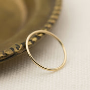 Handmade Half-Round Straight Band (1.3mm) resting on a textured brass dish, from Envero Jewelry on Etsy.