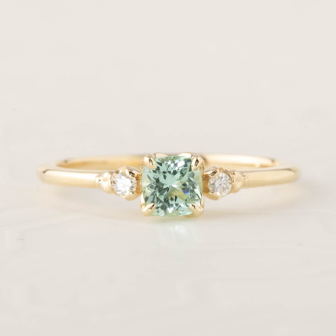 Gold ring featuring a 4.5mm natural cushion cut mint tourmaline and two small brilliant cut diamonds