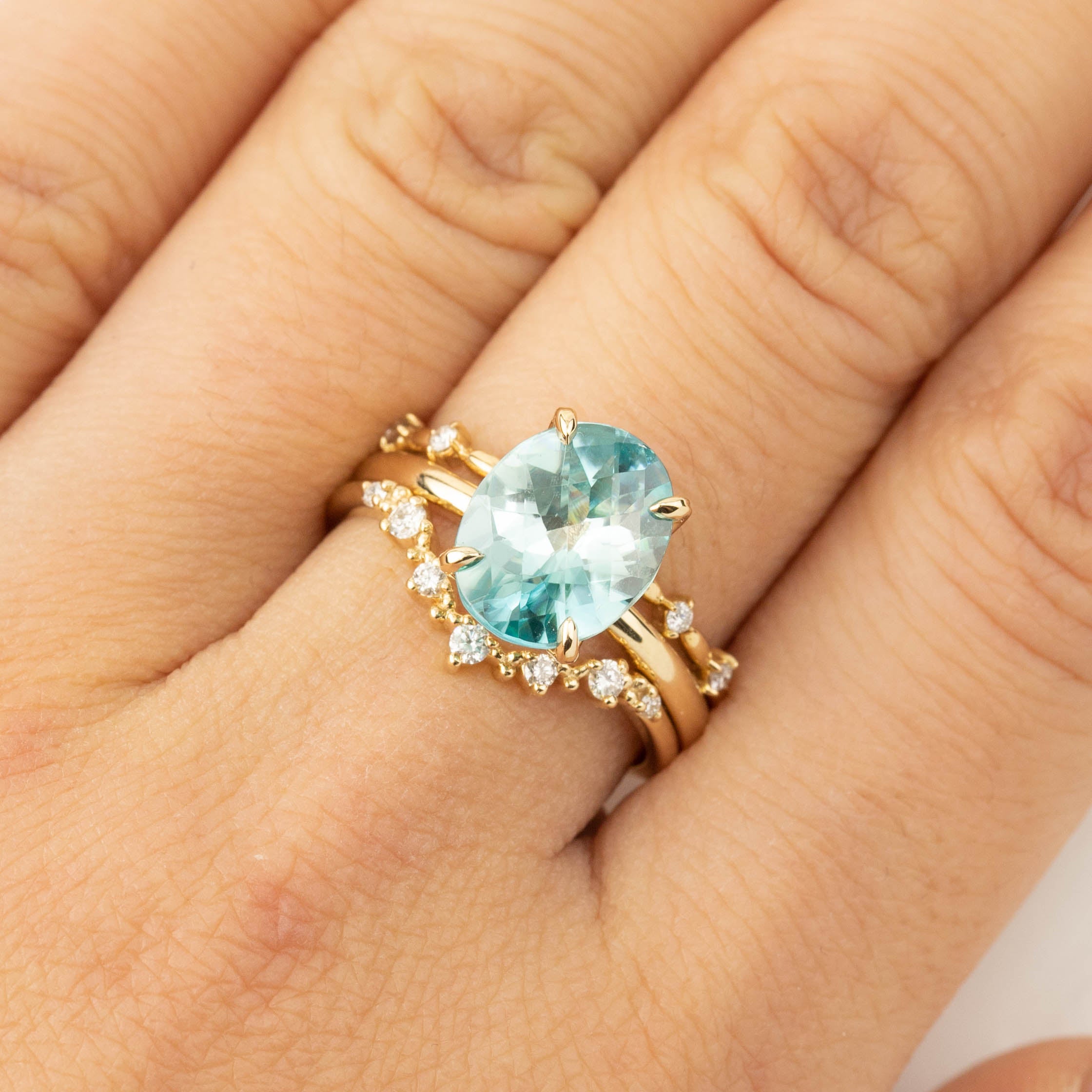 Close-up of hand wearing Sara Ring with 4ct blue zircon checkerboard cut set in 14k yellow gold band