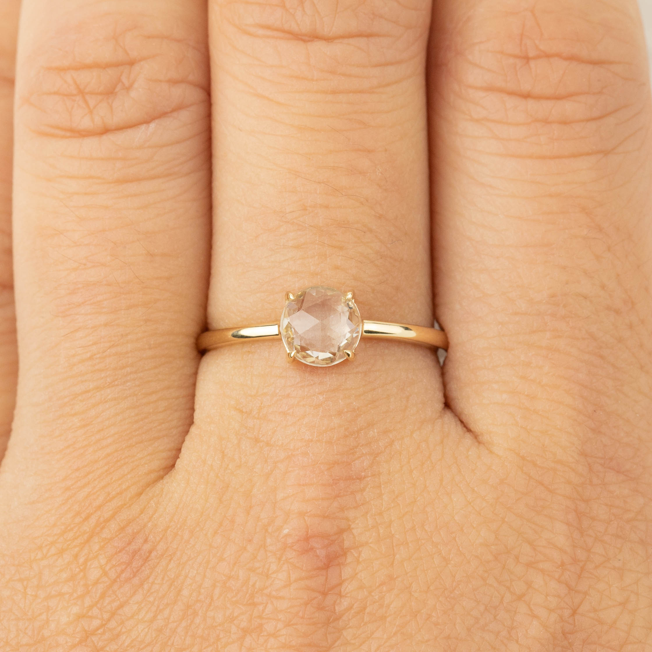 Close-up of Lisa Ring featuring a 0.88ct white sapphire set in recycled 14k gold on a finger.