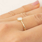 Gold ring with 0.88ct white sapphire in a low profile claw setting worn on finger close-up