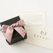 Black Envero gift box with pink bow and two gold-stamped cards on white textured surface