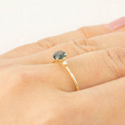 Gold ring with 0.75ct Queensland peacock sapphire and small white diamond on finger, delicate tapered band