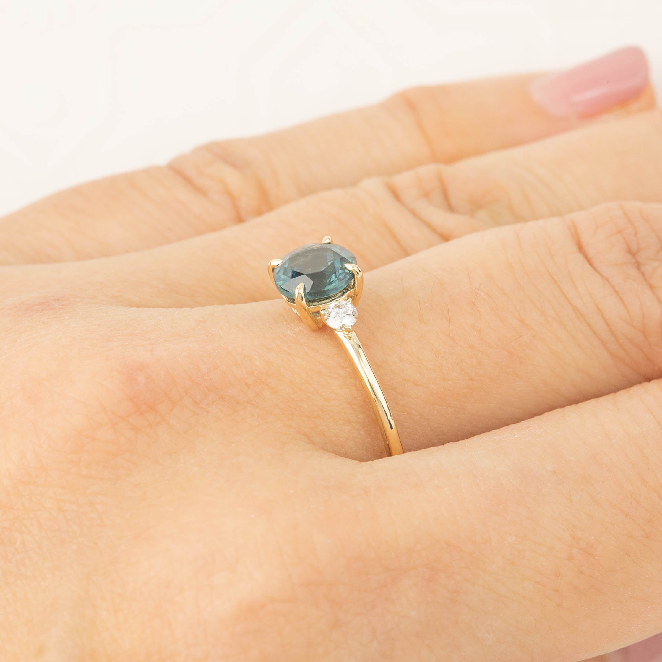 Three stone ring with 1.48ct green Montana sapphire and diamond accents set in recycled 14k gold on hand.