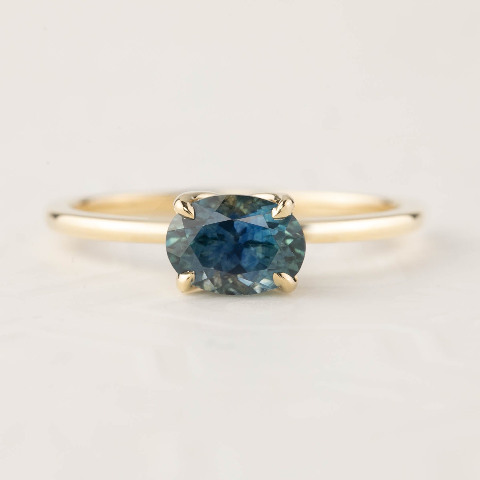 14k yellow gold ring with 1ct mottled blue-green Montana sapphire in a four-prong flower setting, size 7 adjustable.