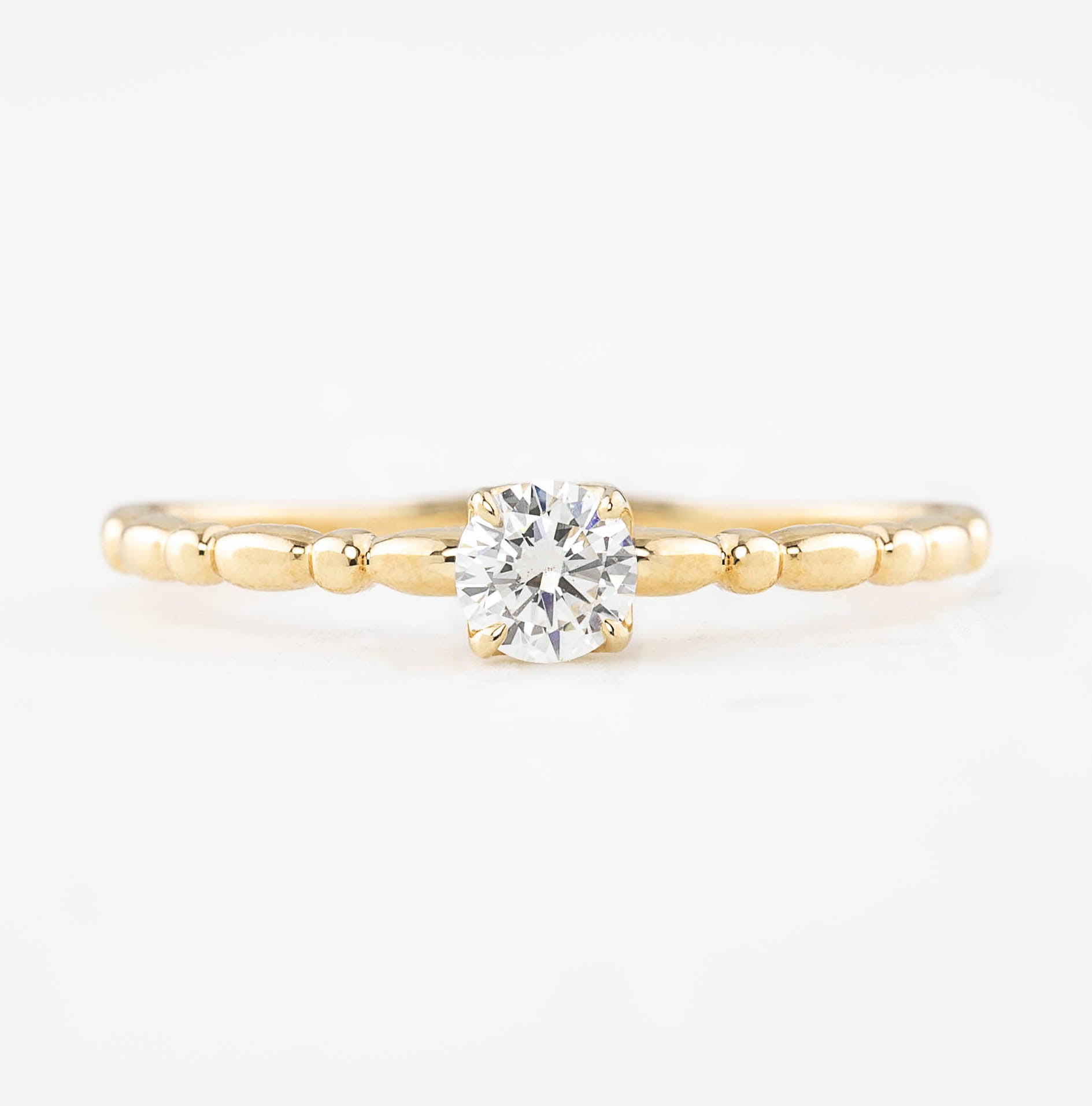 14k yellow gold ring with 0.25ct round brilliant diamond in a four-prong flower setting on a beaded band