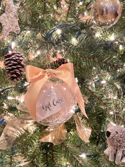 Envero's holiday gift card inside a clear ornament with a satin bow hanging on a decorated Christmas tree branch