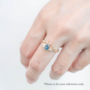 Celine Ring featuring a 0.60ct teal-blue Montana sapphire in a 14k yellow gold with six natural diamond accents on a hand with a stacking diamond band on a hand