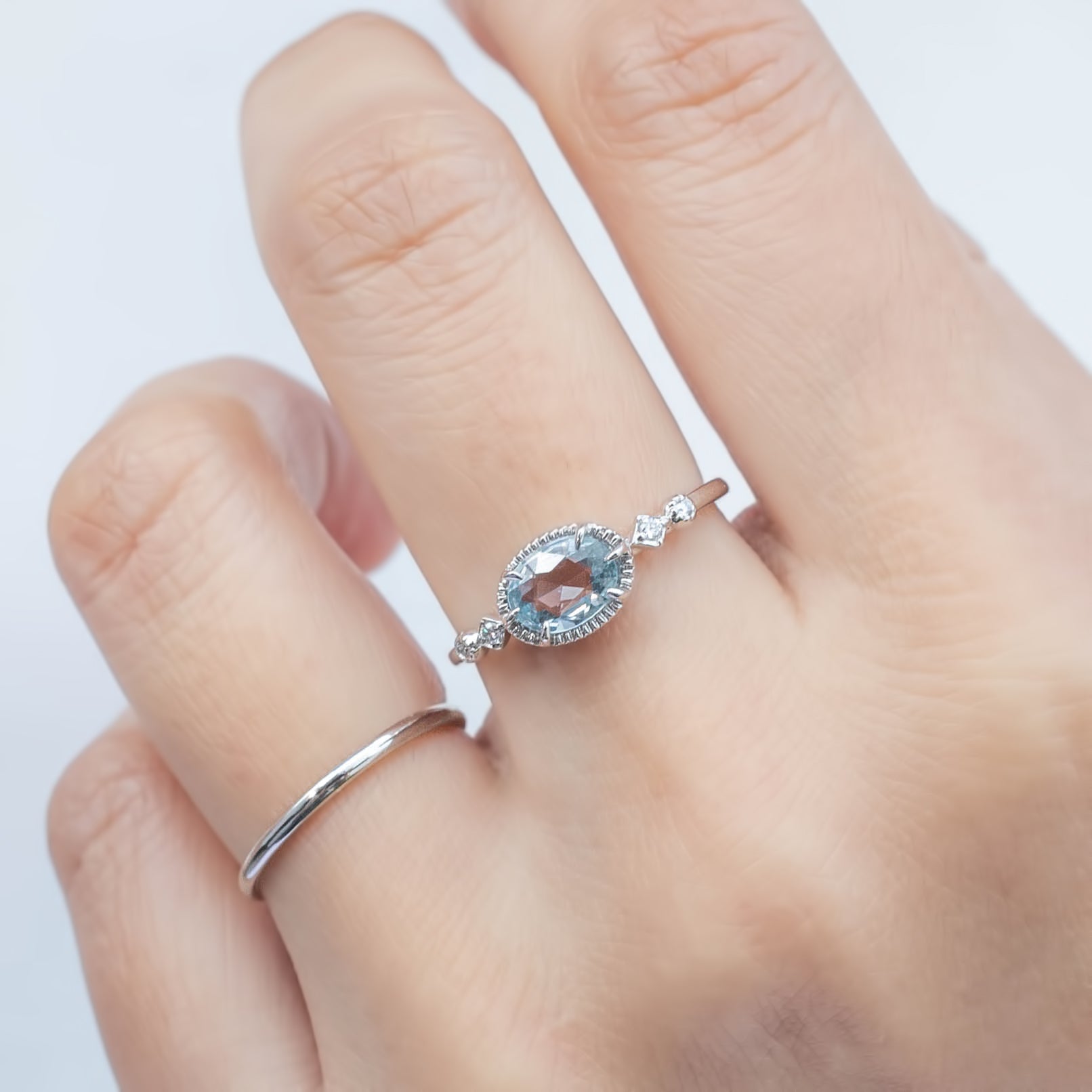 Hand wearing a 0.80ct unheated blue sapphire ring with white accent diamonds set in 14k white gold band