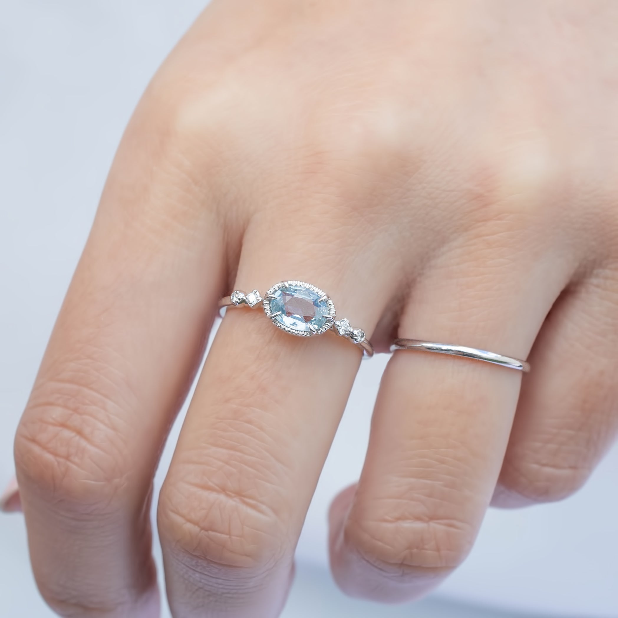 Hand wearing Stella Ring with 0.80ct unheated blue sapphire and white diamonds set in 14k white gold band