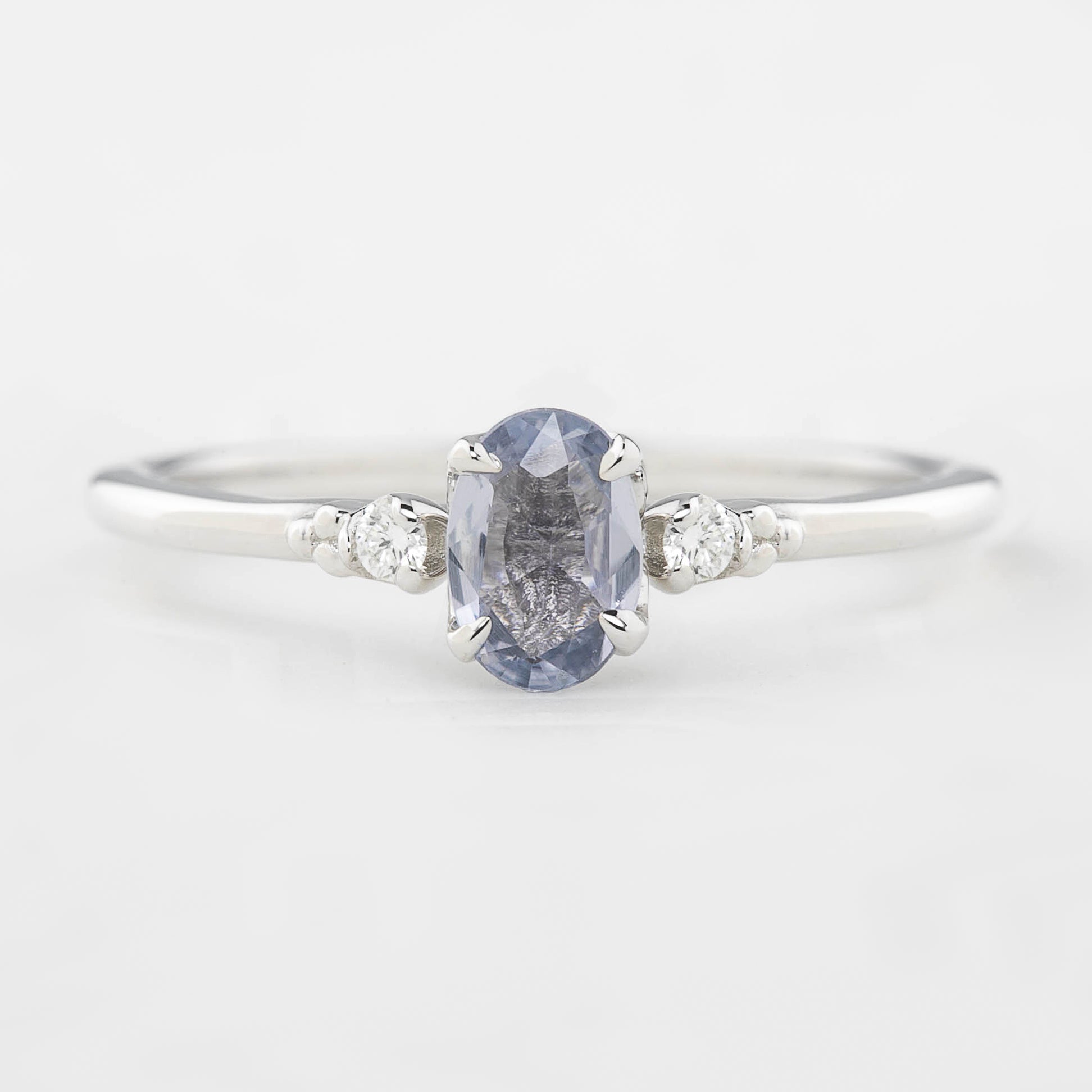 Three 'Estel Rings' with oval-shaped sapphires, in settings of 14k rose gold, 14k white gold, and 14k yellow gold, displayed against a light background., oval shape gemstone