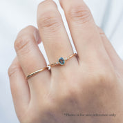Bezel set oval Madagascar sapphire ring with two natural diamond accents in a low profile 14k gold setting on the finger.