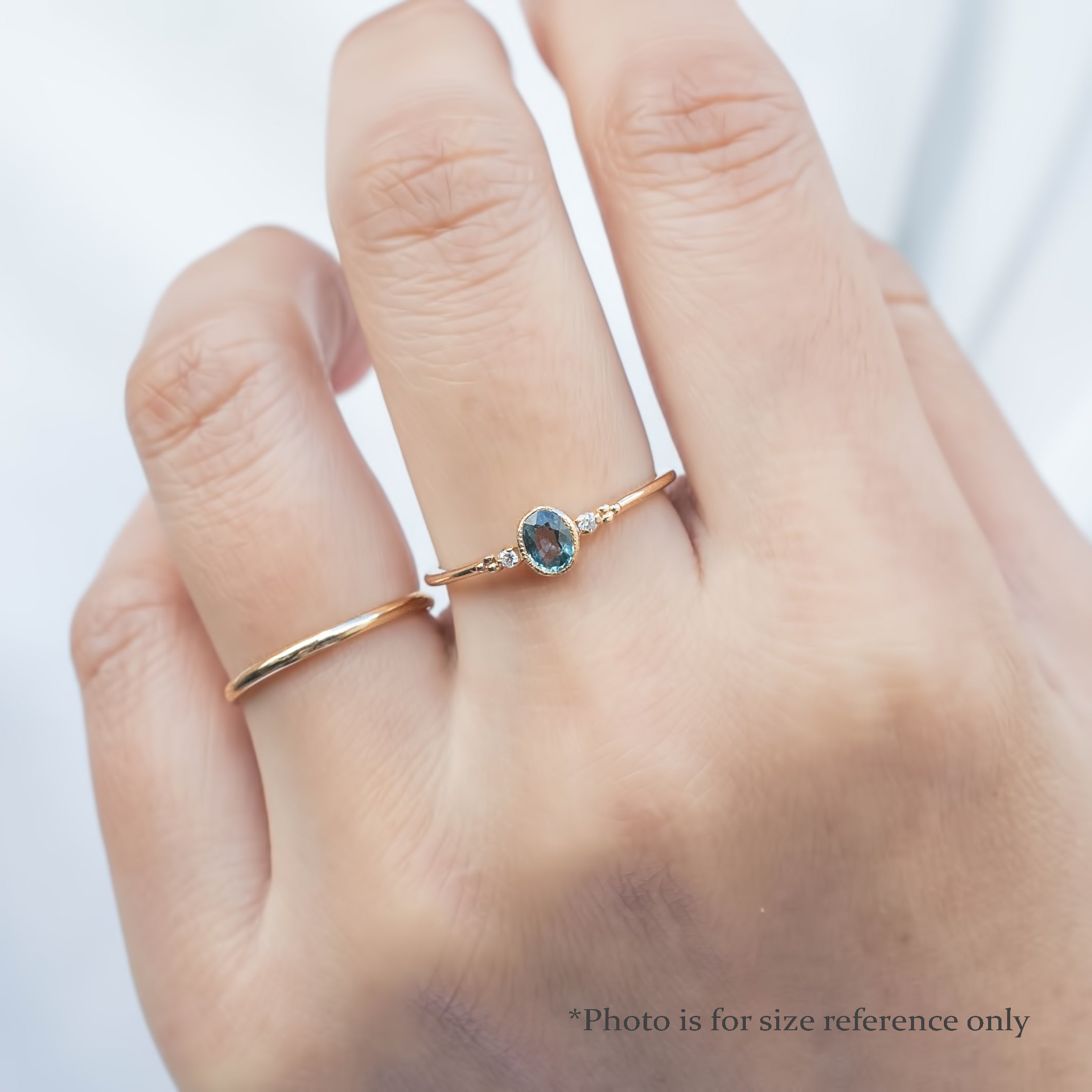 Bezel set oval Madagascar sapphire ring with two natural diamond accents in a low profile 14k gold setting on the finger.