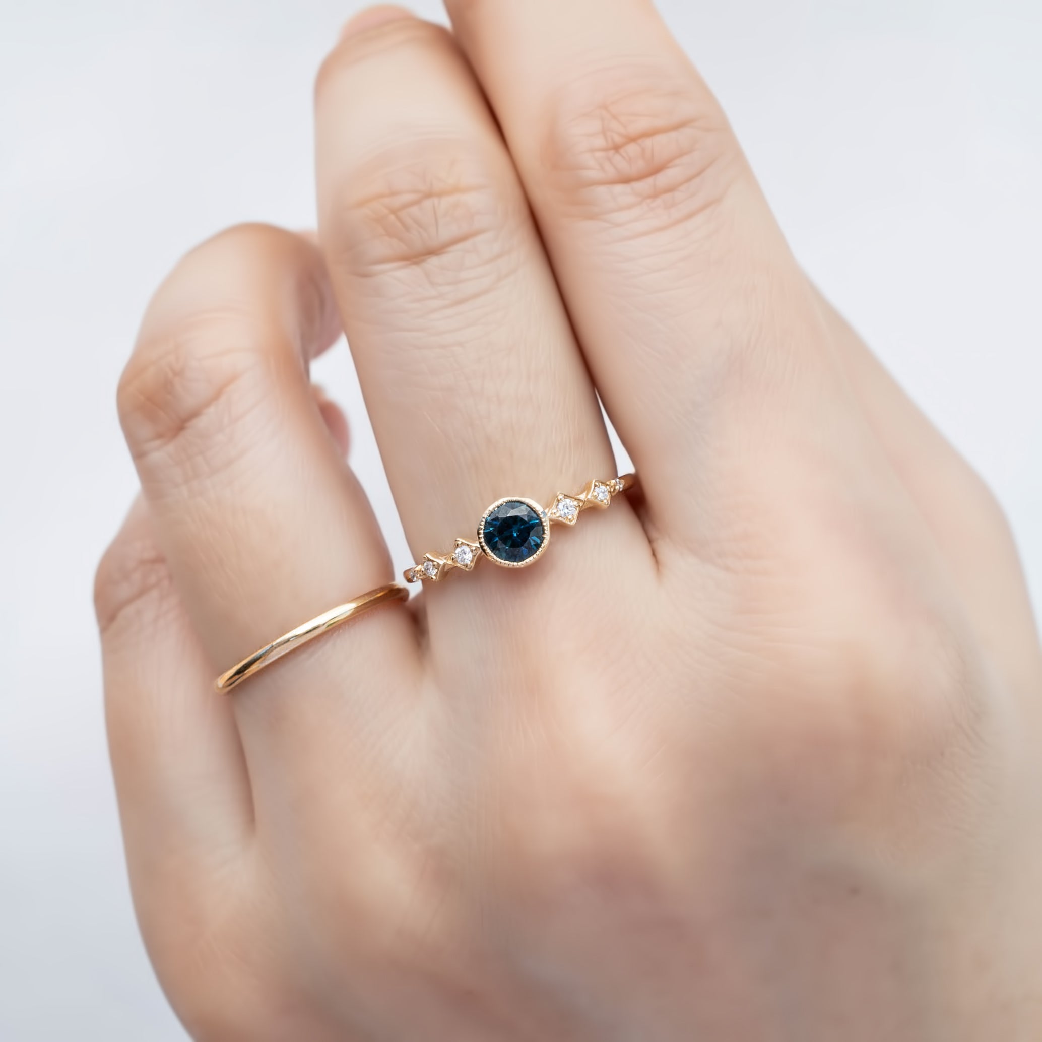 0.50ct teal blue Queensland Sapphire Ring in 14k yellow gold on finger
