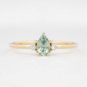 A pear-cut Montana sapphire ring with accent diamonds set in a 14k yellow gold band, displayed against a white background.
