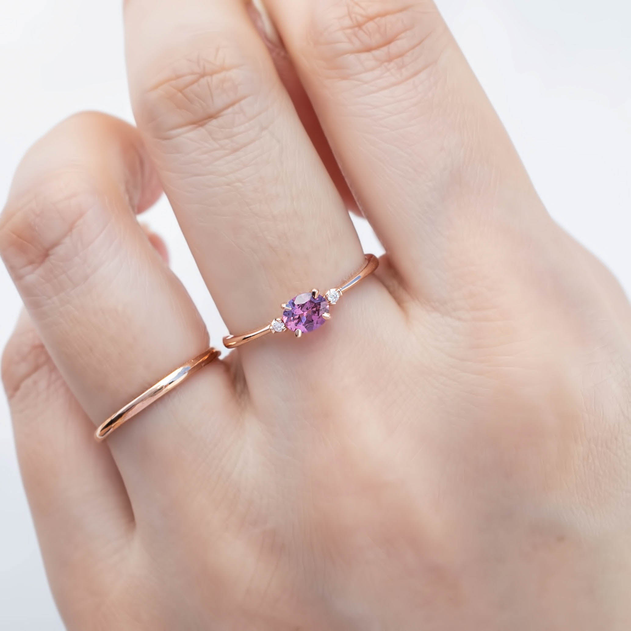 The Emilie 0.45ct Umba pink sapphire ring worn to show the unique horizontal orientation and rose gold band on hand.