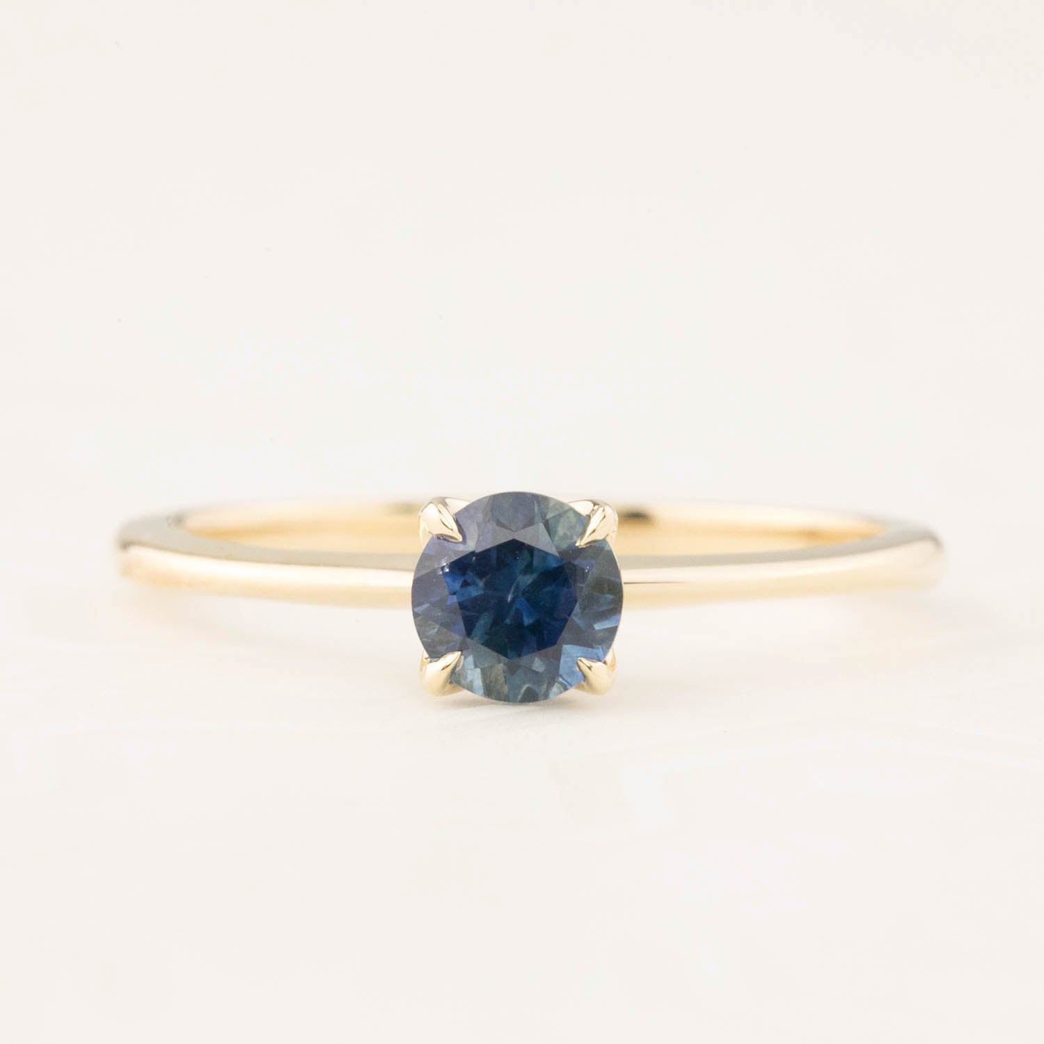 14k yellow gold ring with 0.66ct teal Montana sapphire center stone in delicate tapered band setting