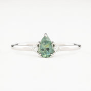 A pear-cut Montana sapphire ring with accent diamonds set in a 14k white gold band, displayed against a white background.