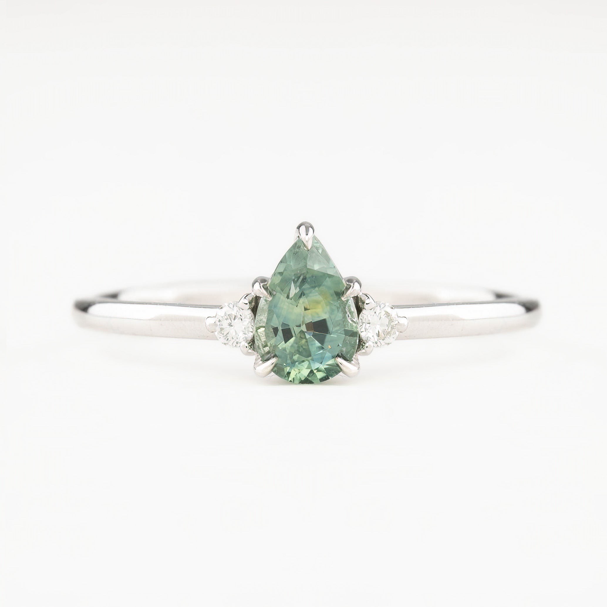 A pear-cut Montana sapphire ring with accent diamonds set in a 14k white gold band, displayed against a white background.